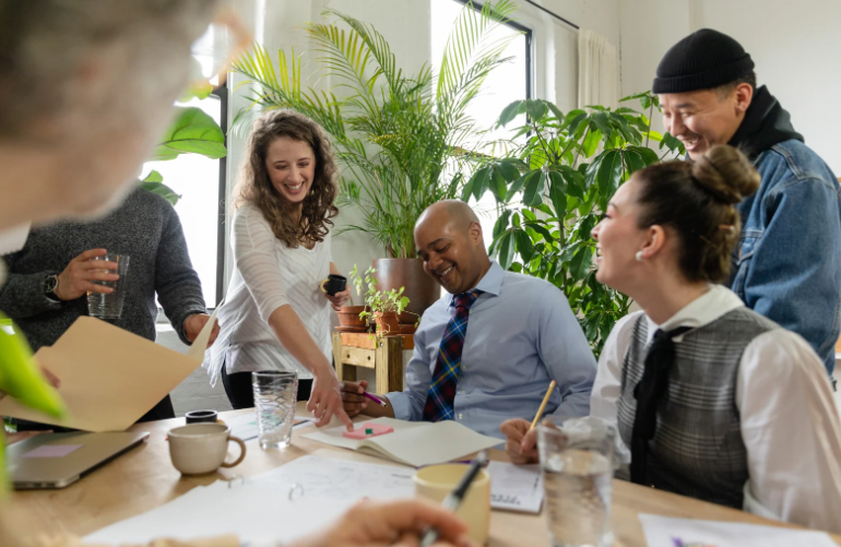 Grupo de personas trabajando juntos con entusiasmo y sonrisas, reflejando un ambiente de colaboración y felicidad laboral Grupo de personas trabajando juntos con entusiasmo y sonrisas, reflejando un ambiente de colaboración y felicidad laboral