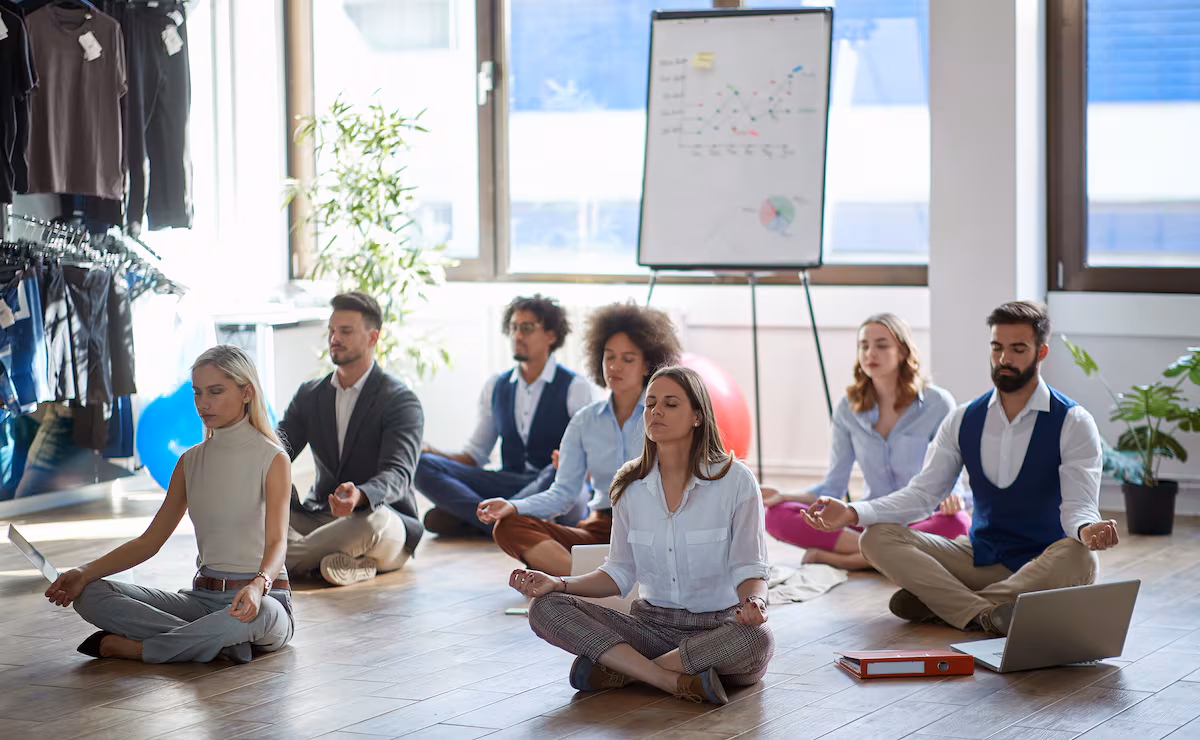 Grupo de trabajadores meditando juntos durante una pausa para mejorar el bienestar laboral.
